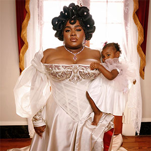 Da'Vine Joy Randolph in a victorian style dress holding a baby